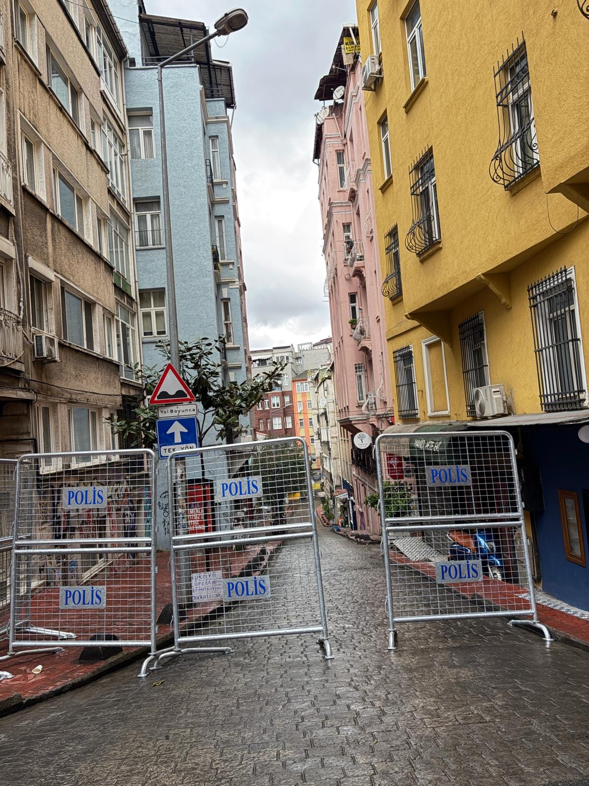 Metal police barriers stamped with "POLİS" seal off a narrow cobbled street in Cihangir